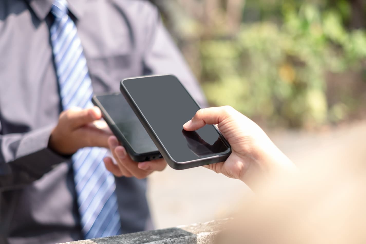 Businessman exchanging contact details by smartphone outdoors