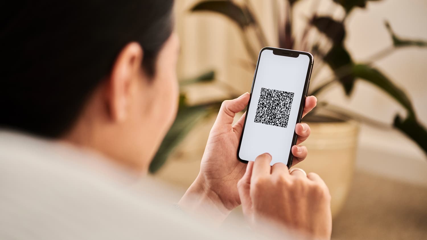 Woman holding a smartphone that displays a QR code to scan