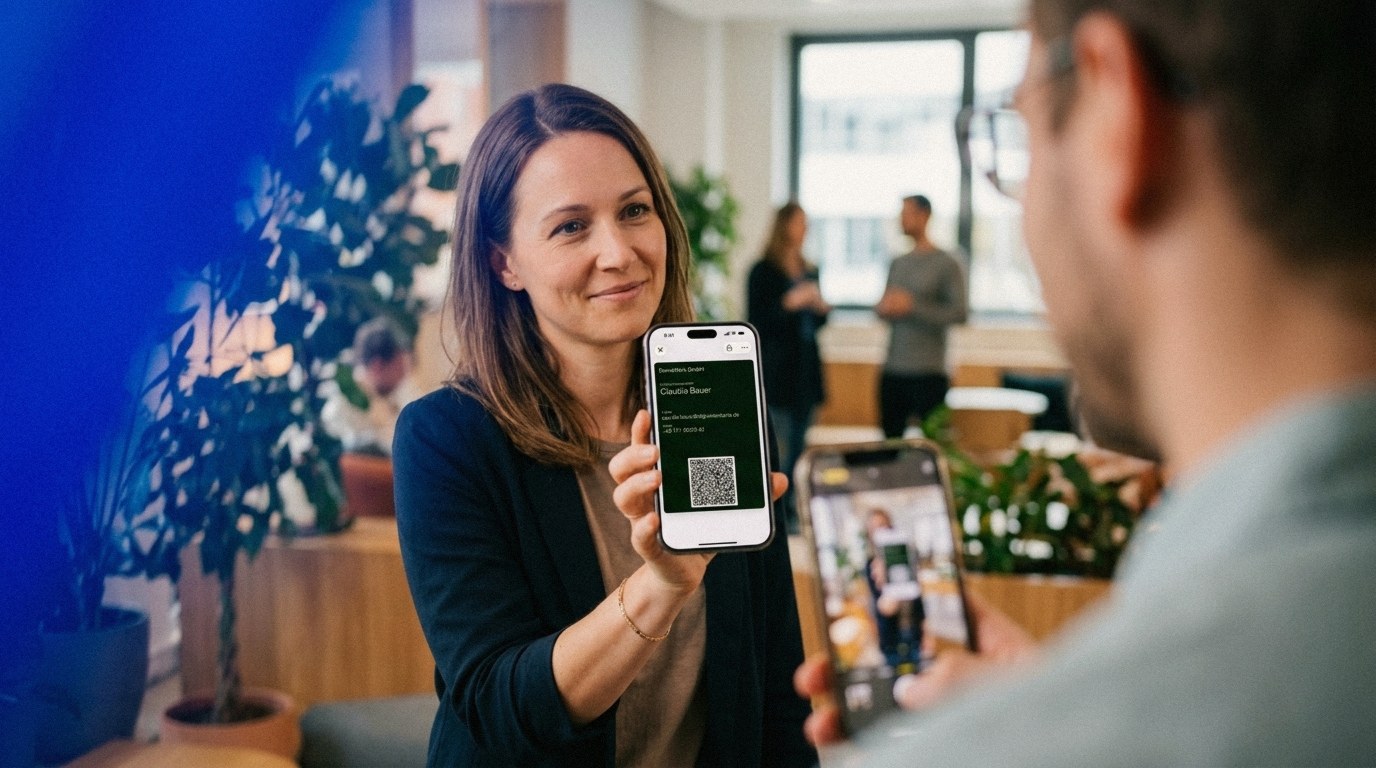A freelancer shows a new contact her digital business card on her phone in a co-working lounge